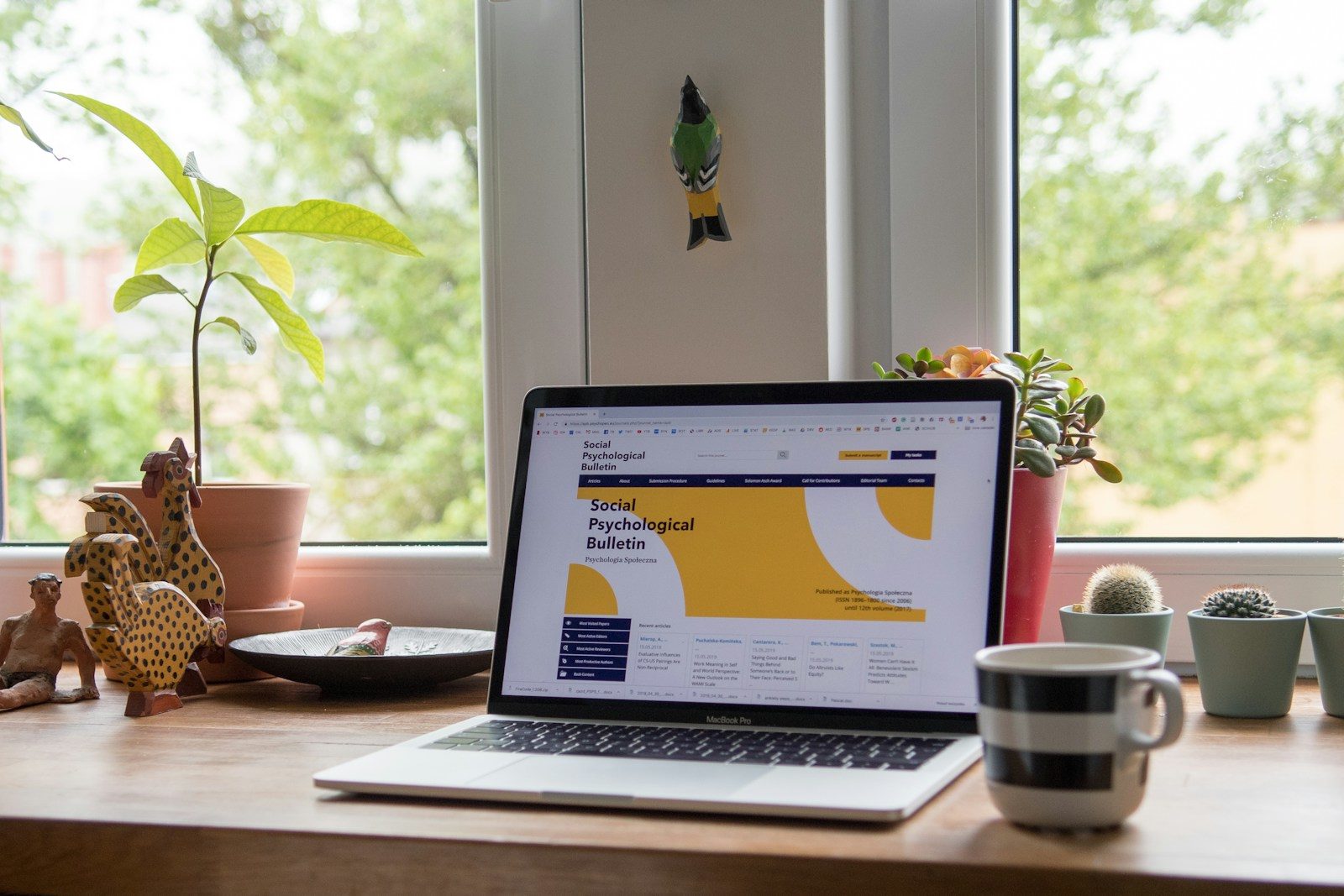 Ordinateur portable ouvert sur un site web, posé sur un bureau près d’une fenêtre